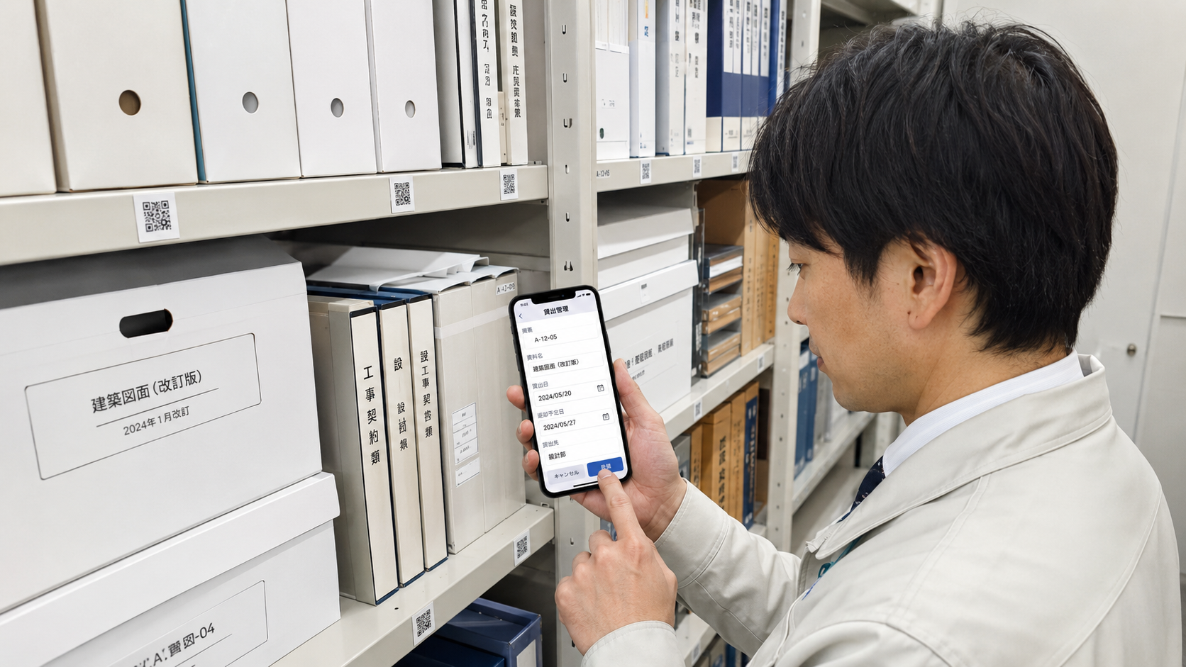 無人書庫のキャビネット棚に貼られたQRコードを社員がスマートフォンで読み取り、図面や契約書の持ち出し管理を行っている写真品質のイメージ。